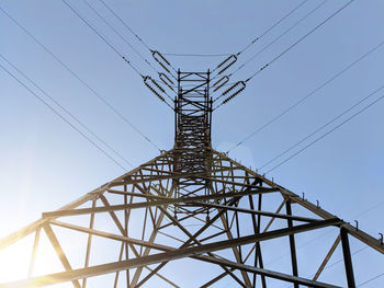 Low angle view of electricity pylon against clear sky during sunny day