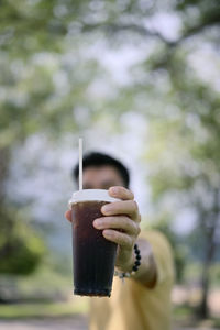 Selective focus ice americano coffee in human hand with bokeh background