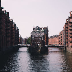 Bridge over river amidst buildings against clear sky