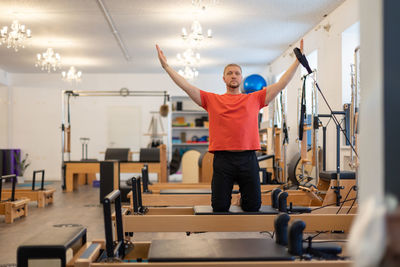 Male fitness pilates trainer shows exercises on special simulators. pilates stretch tables