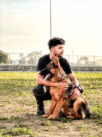 Side view of young man with dog on field