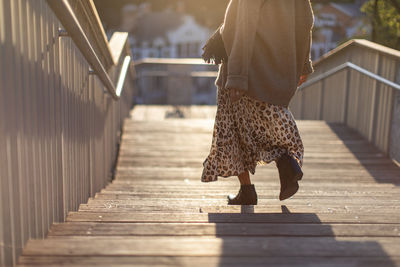 Low section of woman walking on footbridge