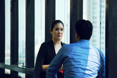Rear view of man standing by window