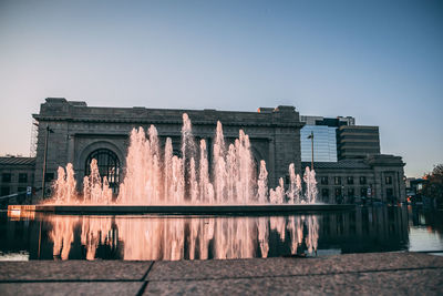 Fountain in city against clear sky