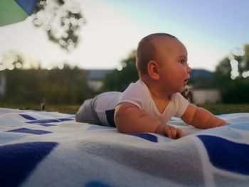 Cute baby boy lying on picnic blanket at park