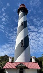 Low angle view of lighthouse by building against sky