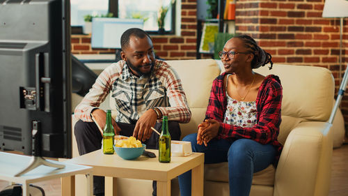 Portrait of smiling friends using digital tablet while sitting at home