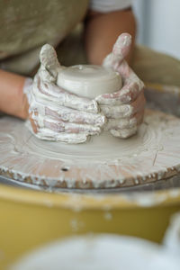 Midsection of woman making pottery in workshop