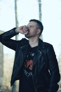 Young man looking away while standing against wall