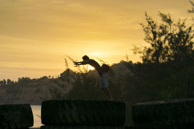 Silhouette man standing by tree against sky during sunset