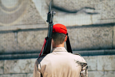 Rear view of man holding umbrella against wall