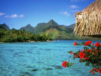 Scenic view of sea in front of mountains against blue sky