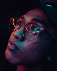 Close-up of man wearing eyeglasses against black background