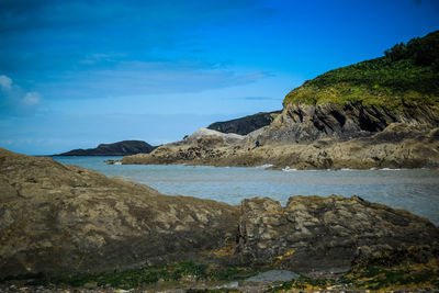 Scenic view of sea and mountains against blue sky