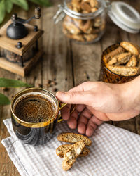 Cup of black coffee with italian traditional cookies cantuccini, human hand, man holding a coffee 