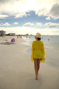 Rear view of woman walking on shore at beach