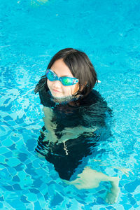 Young child in the pool. fun in swimming pool. wearing goggles on forehead during summer vacation.