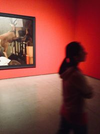 Reflection of woman photographing on mirror against wall