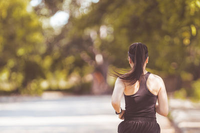 Rear view of woman standing against blurred trees