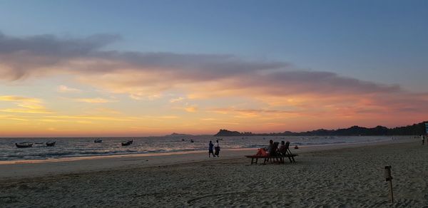 People on beach against sky during sunset