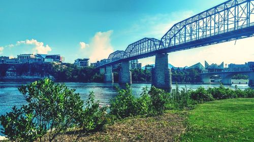 Bridge over river in city against sky