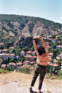 Rear view of man standing on mountain against cityscape