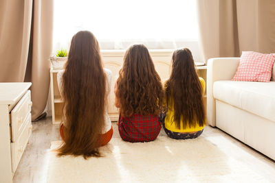 Rear view of women sitting on sofa at home