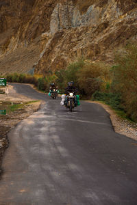 Rear view of people riding motorcycle on road