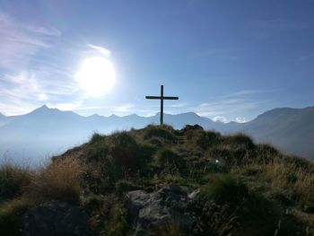 Low angle view of silhouette cross on hill against cloudy sky