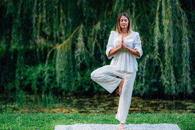 Yoga woman, grounding in nature, tree pose, green background.