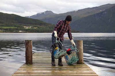 Man with umbrella on lake against mountains