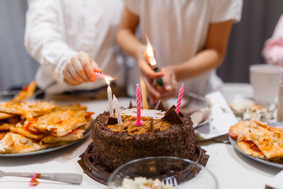 Two boys in light clothes light candles on the cake evening time