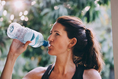 Mature woman drinking water from bottle at beach