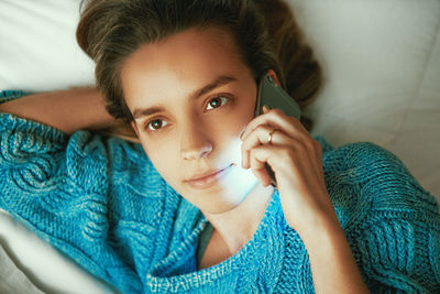 Portrait of young woman lying on bed at home