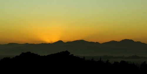 Scenic view of silhouette mountains against orange sky
