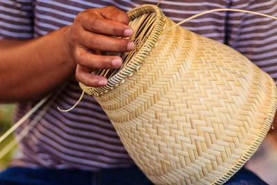 Midsection of man making wicker decoration