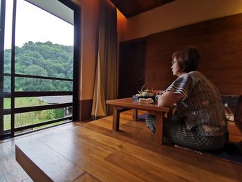 Side view of woman sitting on table at home