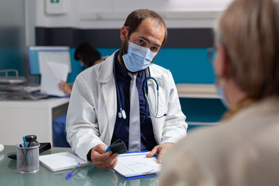 Doctor wearing mask talking with patient