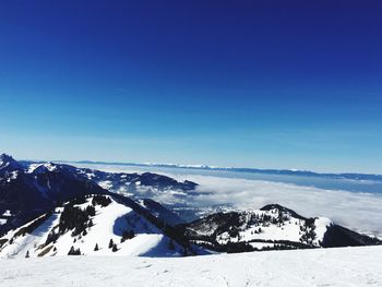 Scenic view of snowcapped mountains against blue sky