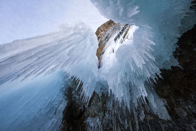 Icicles on snow covered mountain against sky