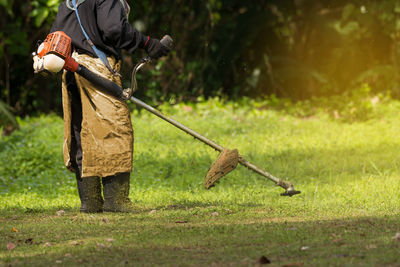 Low section of man mowing grass