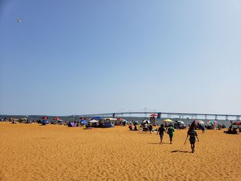 People on beach against clear sky