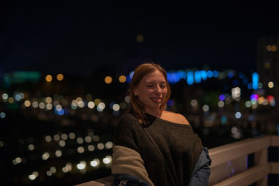 Fashionable young woman in city at night