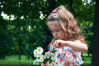 Cute girl holding bouquet at park