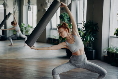 Beautiful woman holding exercise mat at studio