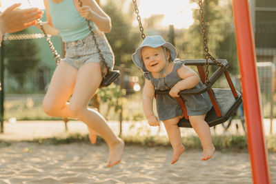 Full length of young woman swinging at playground