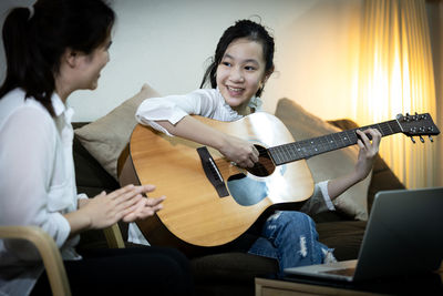 Mother teaching guitar to daughter at home