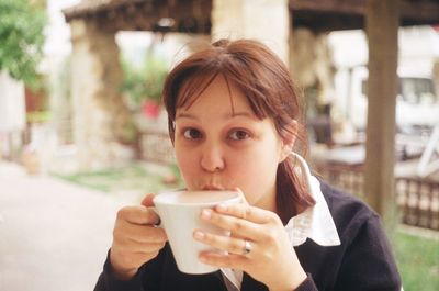 Portrait of young woman having hot chocolate drink in yard