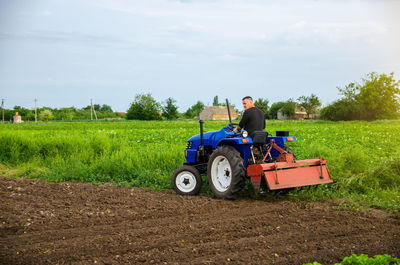 A farmer with a cultivation unit on a tractor rides to cultivate a field. milling soil, crushing 