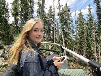 Beautiful young woman texting on ski lift